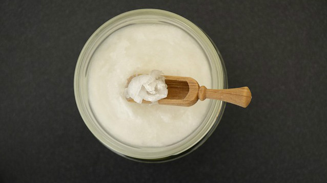 A wooden scooper in a jar of coconut oil