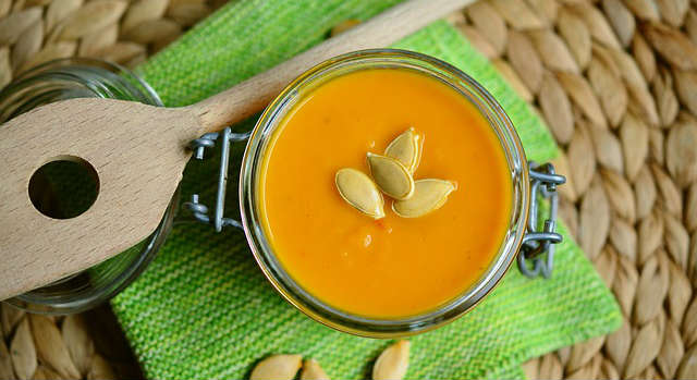 Pumpkin soup in a mason jar with pumpkin seeds sprinkled on top