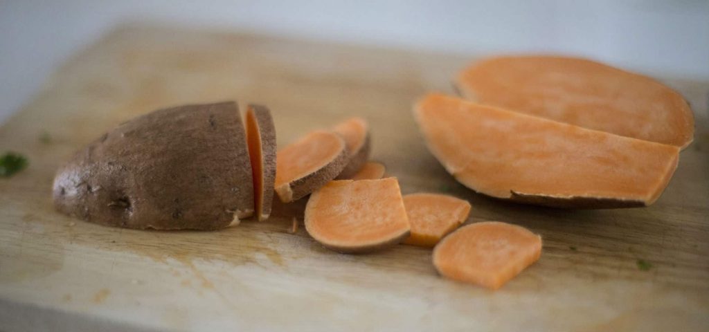 Chopped sweet potato on a cutting board with the skin on