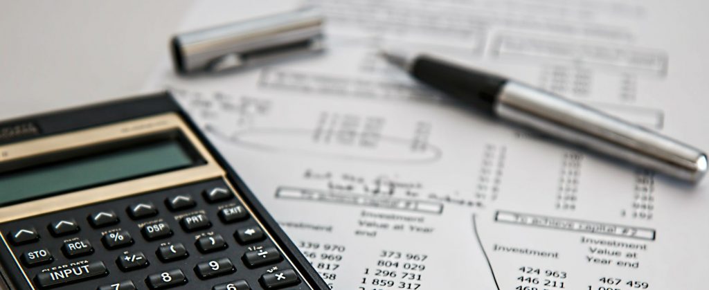 A calculator and pen sitting on top of pet insurance policy paperwork