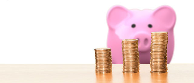 Stacks of change in front of a pink piggy bank