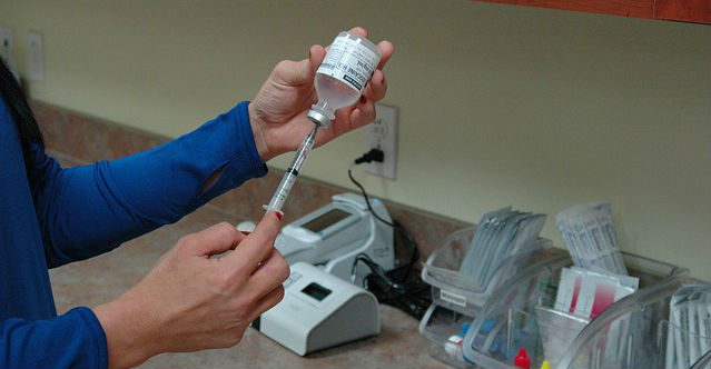 A vaccine being pulled out of a vial and filling up a syringe