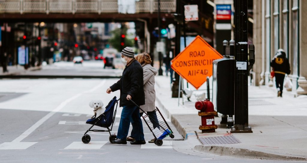 A man and woman are pushing a dog in a stroller while wearing face masks in Chicago