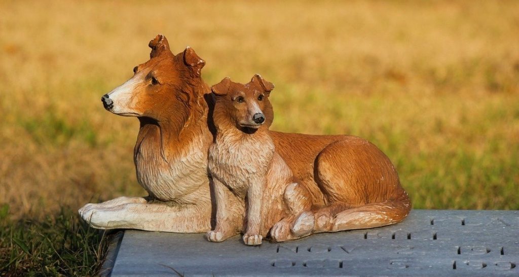 Ceramic dogs situated on top of a headstone outside