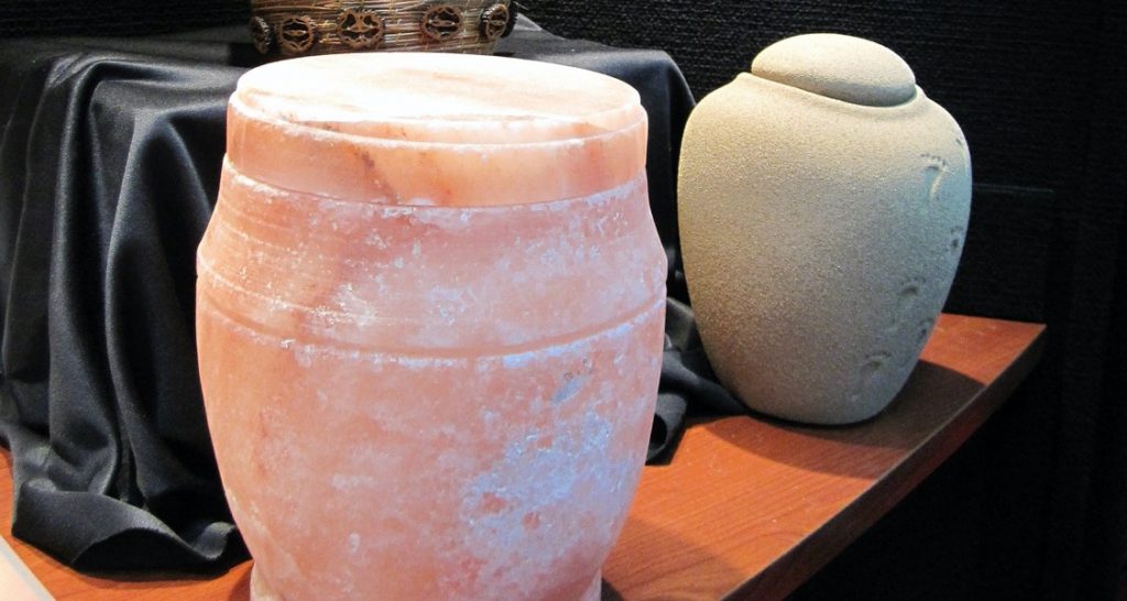Cremation urns of different styles are situated on a wooden table
