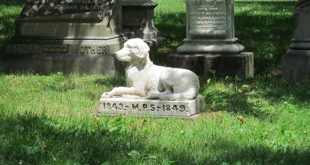 A stone dog grave in a graveyard