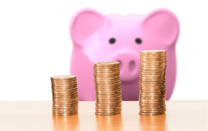 Pink piggy bank with coins in front