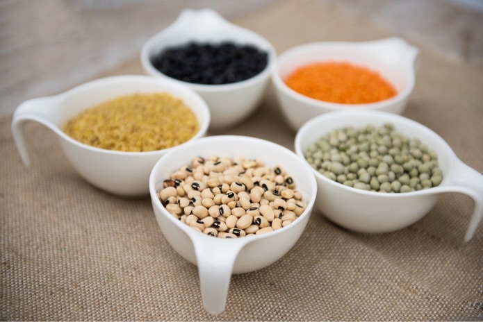 An assortment of different pulses in white bowls