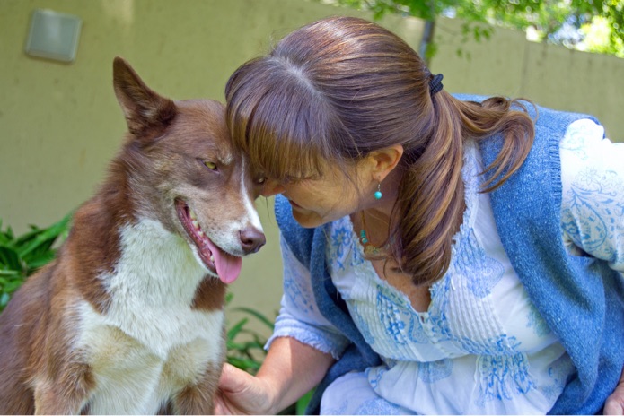 A woman presses her head endearingly against a dog's head