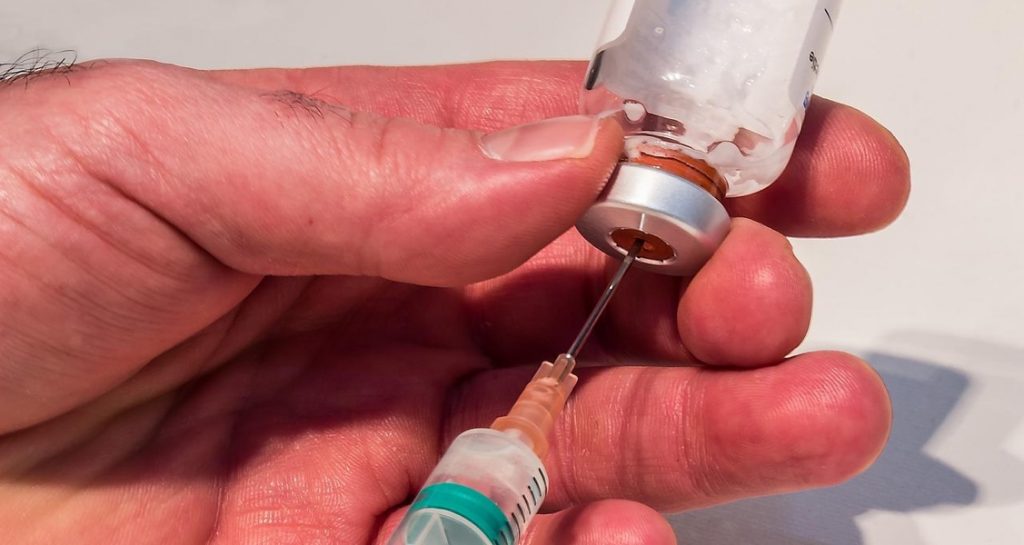 The needle of an injectable syringe is inside of a medication vial