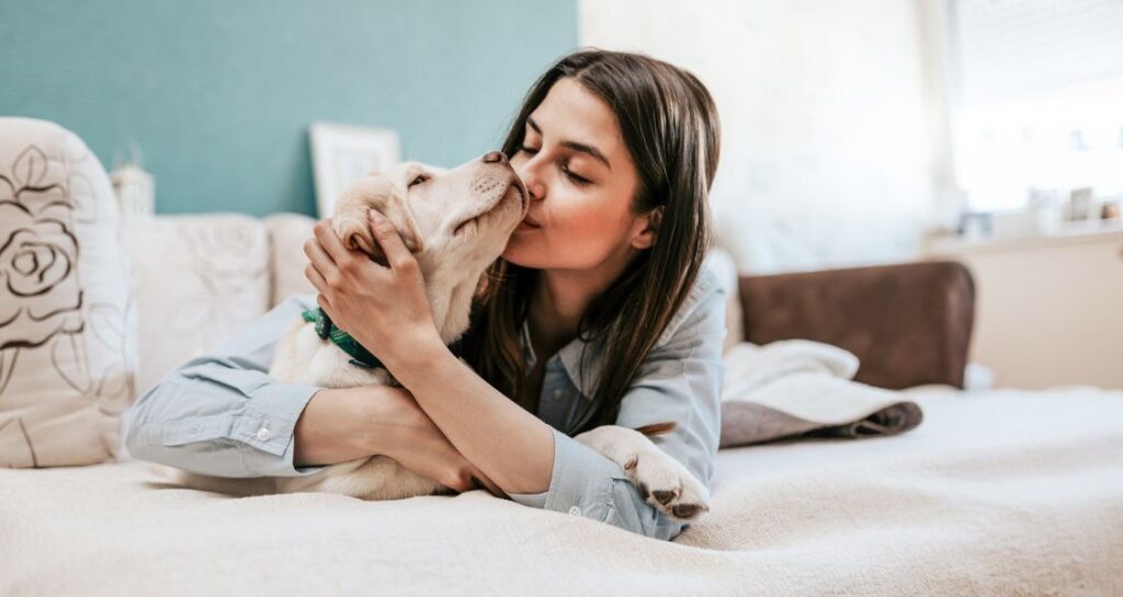 A woman is kissing a dog in bed