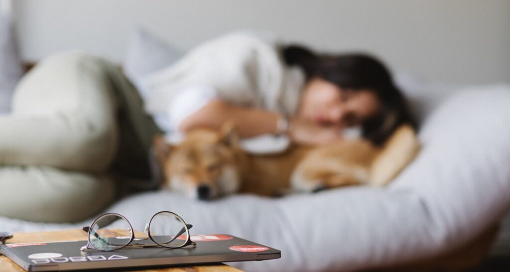 A woman is sleeping with her dog in bed