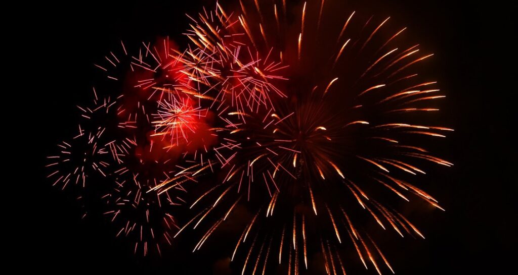 Red colored fireworks are set off in the night sky