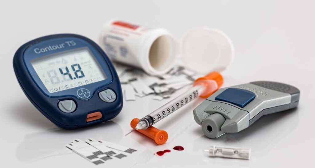An image showing a glucometer, test strips, syringe, and lancet for diabetes