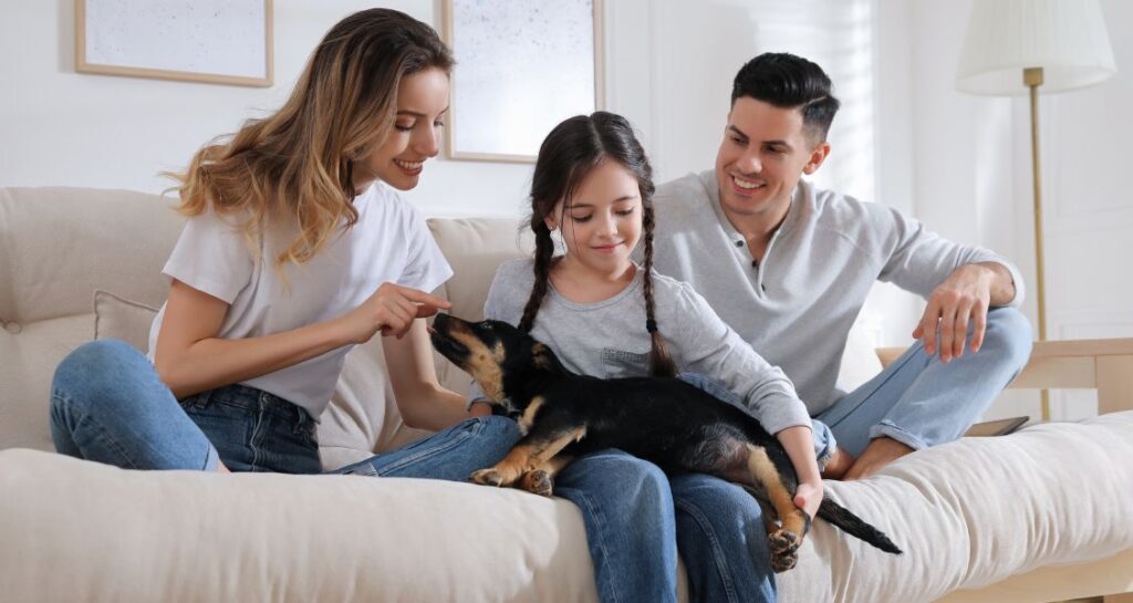 A family is sitting with their dog on a couch